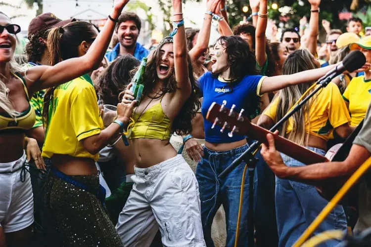 Pessoas celebrando ao ar livre com música e roupas nas cores do Brasil