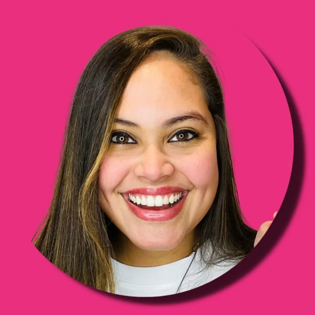 Débora Mumma sorrindo em retrato sobre fundo rosa