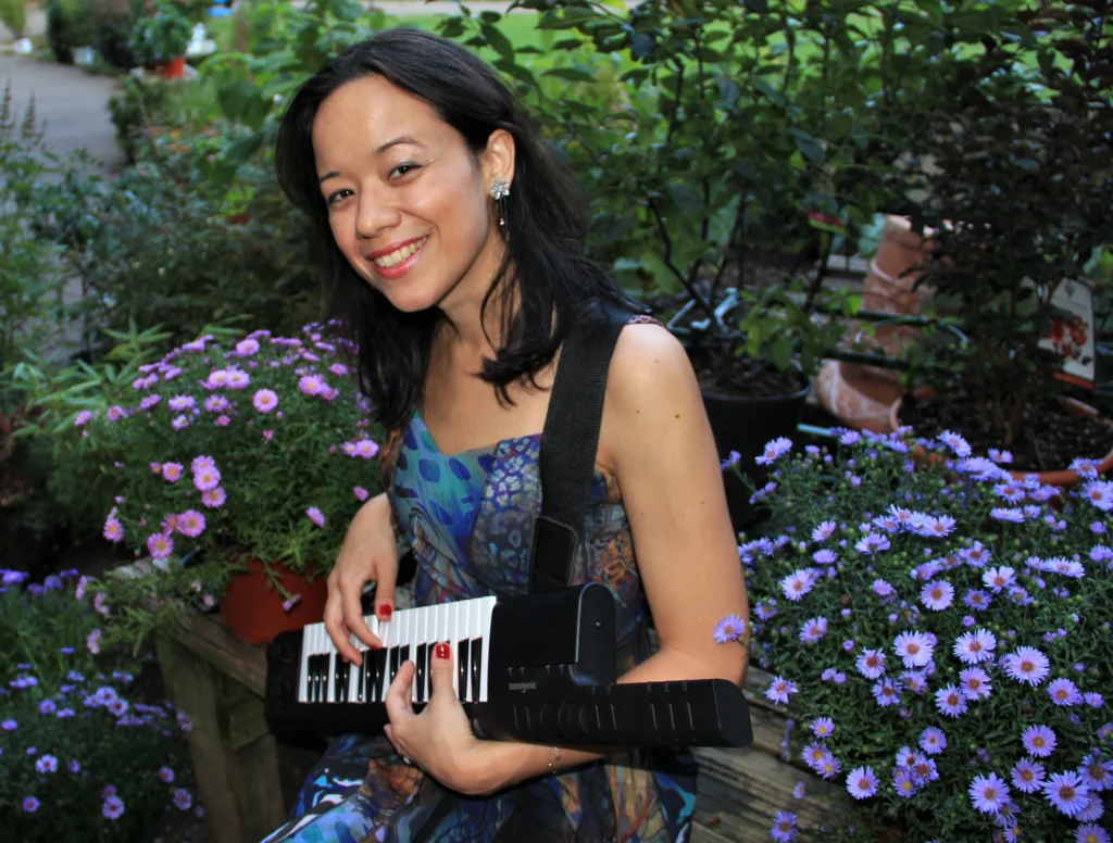 Isabella Mendes com instrumento musical em jardim
