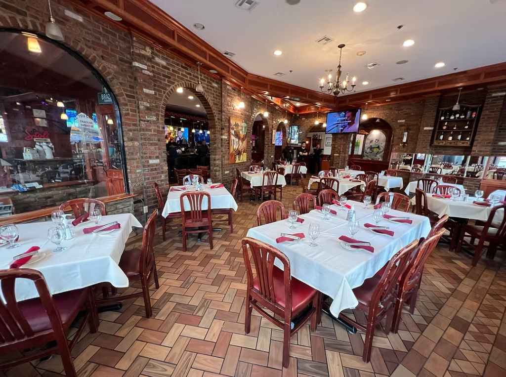 Salão interno da Casa Nova Grill em Newark, com mesas preparadas, paredes de tijolos e decoração brasileira.