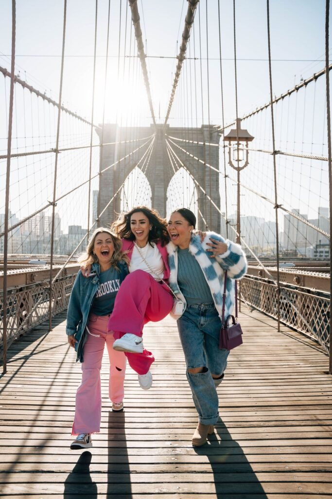 Três amigas sorrindo durante ensaio fotográfico na Brooklyn Bridge