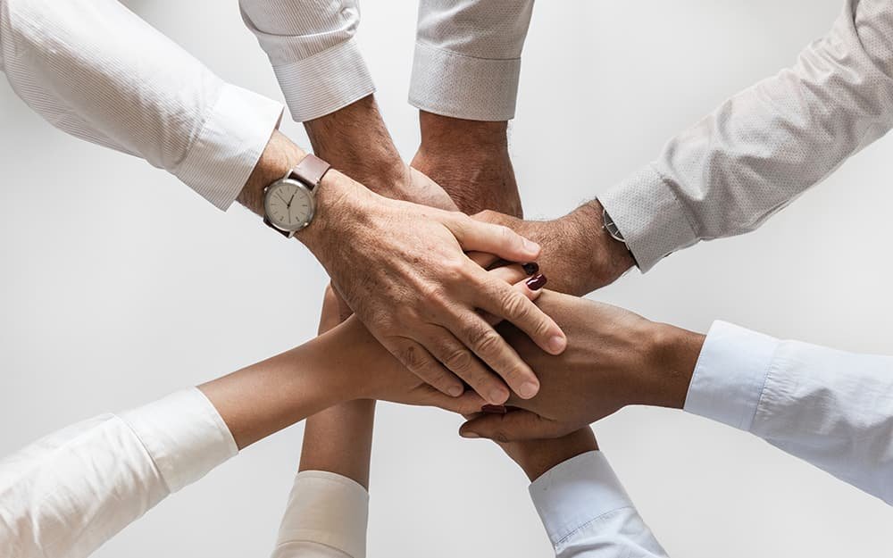 Mãos reunidas representando atendimento em equipe da Lilly Voyages