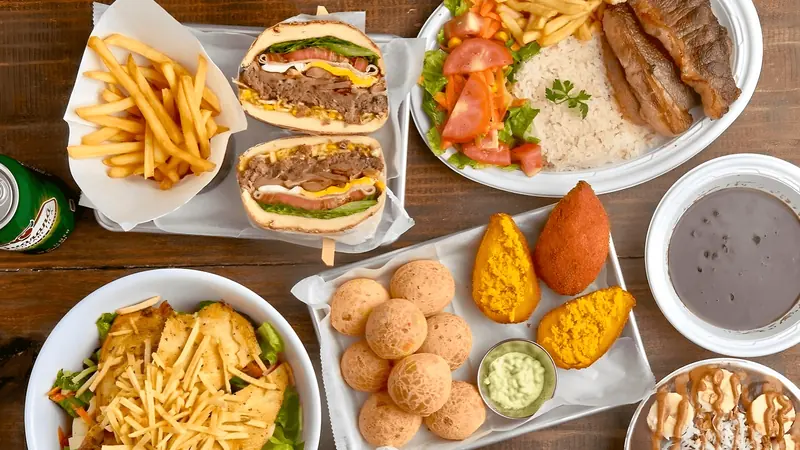 Mesa com pão de queijo, lanches e pratos brasileiros do New York Pão de Queijo